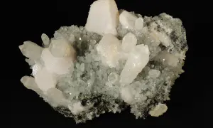 Ein Cluster aus klaren, milchigen Kristallen, die wie gefrorene Tropfen aussehen, bildet einen Teil eines Manganocalcit-Exemplars.