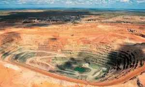 Tiefer Krater einer Mine, wo der **diamanten abbau** stattfindet. Grüne Wasseransammlungen am Grund.
