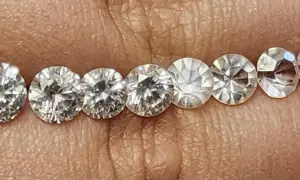 Reihe von geschliffenen Steinen, die auf einer Hautoberfläche liegen. Es ist schwierig, diamant oder zirkonia erkennen, da sie sehr ähnlich aussehen.