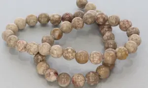 Zwei Stränge mit runden, beige-braunen Korallenperlen, die die Bedeutung von Schutz und Heilung symbolisieren.