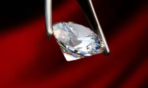 Ein funkelnder Diamant, gehalten von einer Pinzette, zeigt sein gesamtes Spektrum an Farben. Was ist ein brillant? Ein Stein, der Licht bricht und verzaubert.