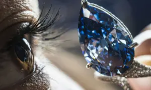 Ein Auge blickt auf einen funkelnden blauen Diamanten, dessen Wert unermesslich ist.
