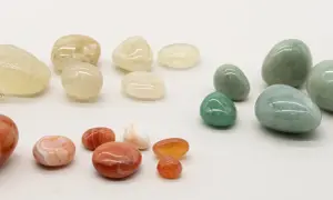 Eine Sammlung von polierten Steinen in Gelb-, Grün- und Rottönen. Der gelbe Stein steht für Optimismus und Freude.