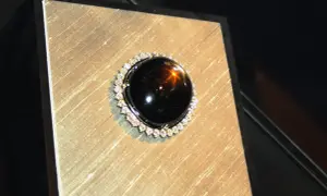 Ein glänzender schwarzer Saphir mit einem Stern-Effekt, umgeben von kleinen Diamanten. Seine geheimnisvolle schwarzer saphir bedeutung fasziniert.