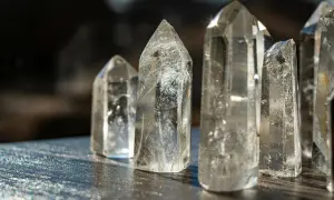 Klare Quarzkristalle, die als heilstein schlaf dienen, stehen auf einer dunklen Oberfläche.