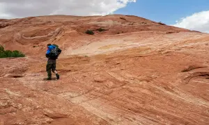 Wanderer auf rotem Felsplateau, wo die Moqui Marbles sich bewegen.