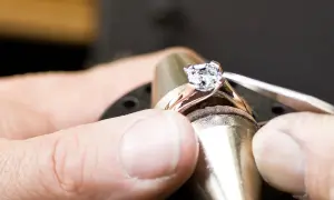Ein Juwelier setzt einen funkelnden Diamanten, einen kostbaren Edelstein, in eine Ringschiene ein.