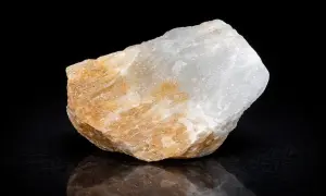 Ein Stück Alabaster, dessen Bedeutung in seiner Reinheit und seinem sanften Glanz liegt, schimmert in Weiß und Beige vor schwarzem Hintergrund.