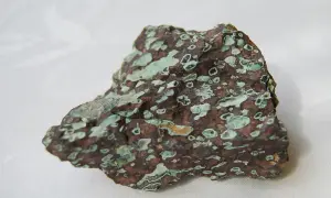 Ein roher, brauner Stein mit hellgrünen Einschlüssen, der an den Edelstein Türkis erinnert.