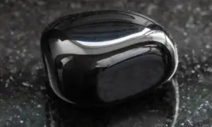 Glatter, glänzender onyx stein liegt auf einer dunklen, gesprenkelten Oberfläche.