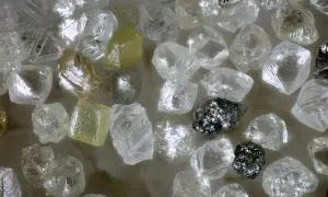 Unbearbeitete Diamanten, einige gelblich, andere klar, glänzen. Ihre Seltenheit und Härte erklären, warum sind Diamanten so wertvoll.