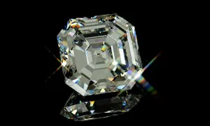 Ein glitzernder Diamant im Asscher Schliff, der auf schwarzem Hintergrund reflektiert und Regenbogenlicht bricht.