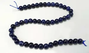 Eine Kette aus tiefblauen Sodalith-Perlen, die auf einem weißen Hintergrund liegen.