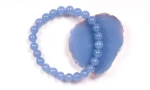 Armband aus hellblauen Perlen, die auf einem Stück Angelit Stein liegen.
