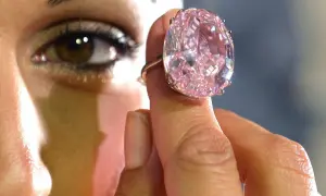 Ein riesiger, pinker Diamantring wird von einer Hand gehalten. Man fragt sich, wie viel kostet ein Kilo Diamant?