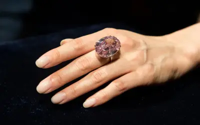 Ein großer, ovaler rosa Diamantring, der den teuersten Diamant der Welt Preis repräsentiert, wird an einer Hand getragen.