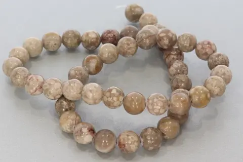 Zwei Stränge mit runden, beige-braunen Korallenperlen, die die Bedeutung von Schutz und Heilung symbolisieren.