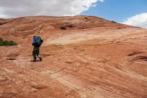 Wanderer auf rotem Felsplateau, wo die Moqui Marbles sich bewegen.
