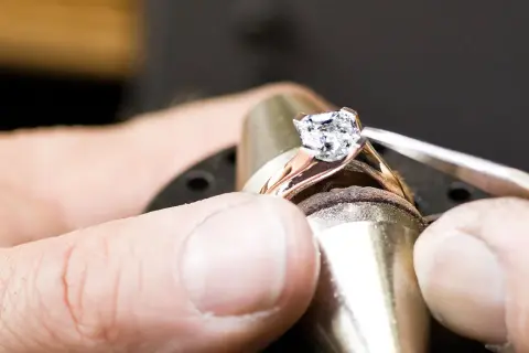 Ein Juwelier setzt einen funkelnden Diamanten, einen kostbaren Edelstein, in eine Ringschiene ein.