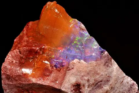 Ein roher Feueropal mit leuchtenden Farben, dessen feurige Wirkung durch das Spiel von Licht und Farbe im Stein fasziniert.