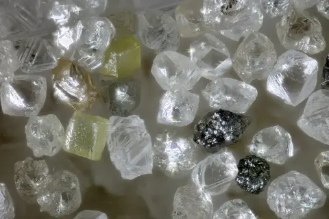 Unbearbeitete Diamanten, einige gelblich, andere klar, glänzen. Ihre Seltenheit und Härte erklären, warum sind Diamanten so wertvoll.