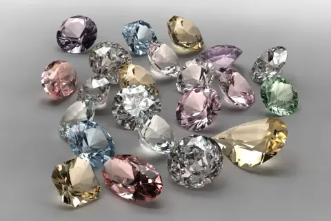 Bunte Edelsteine, was ist wertvoller als Diamant? Ein Haufen funkelnder, geschliffener Juwelen in Rosa, Blau, Grün und Gelb.