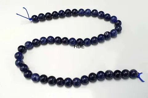Eine Kette aus tiefblauen Sodalith-Perlen, die auf einem weißen Hintergrund liegen.