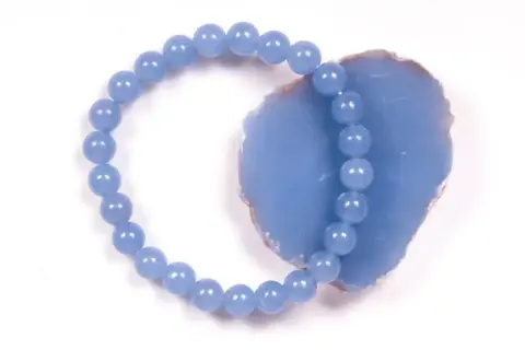 Armband aus hellblauen Perlen, die auf einem Stück Angelit Stein liegen.