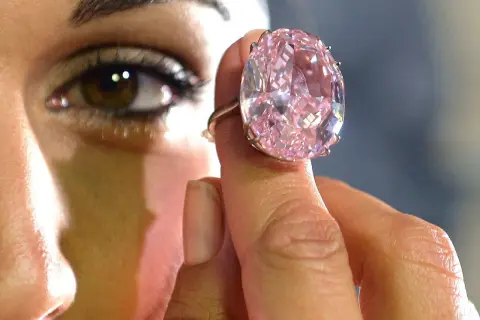 Ein riesiger, pinker Diamantring wird von einer Hand gehalten. Man fragt sich, wie viel kostet ein Kilo Diamant?