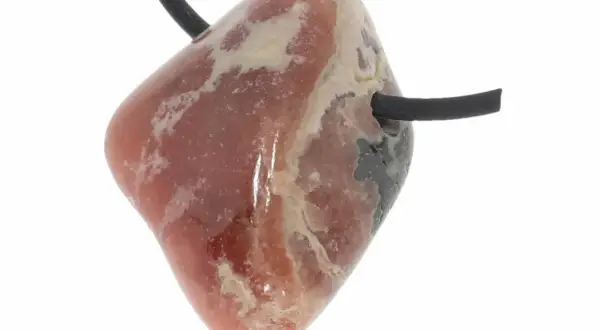 Ein facettierter Rhodochrosit-Anhänger mit schwarzem Band. Seine rosa Farbe und die hellen Einschlüsse deuten auf seine positive Rhodochrosit Wirkung hin.