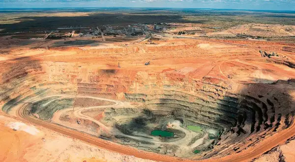 Tiefer Krater einer Mine, wo der **diamanten abbau** stattfindet. Grüne Wasseransammlungen am Grund.