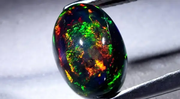 Ein faszinierender schwarzer Opal mit lebendigen Farbspielen von Grün, Rot und Gelb. Seine Wirkung ist magisch.