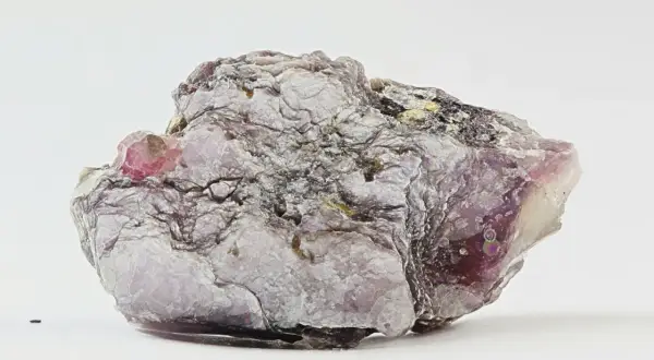 Ein schuppiger, lila-grauer Lepidolith-Stein mit glänzenden Oberflächen und einem kleinen, rosa Kristall.