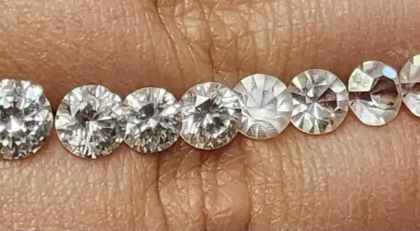 Reihe von geschliffenen Steinen, die auf einer Hautoberfläche liegen. Es ist schwierig, diamant oder zirkonia erkennen, da sie sehr ähnlich aussehen.