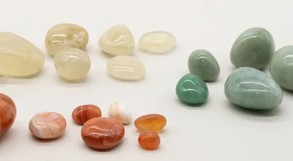 Eine Sammlung von polierten Steinen in Gelb-, Grün- und Rottönen. Der gelbe Stein steht für Optimismus und Freude.