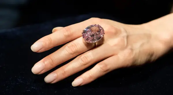 Ein großer, ovaler rosa Diamantring, der den teuersten Diamant der Welt Preis repräsentiert, wird an einer Hand getragen.