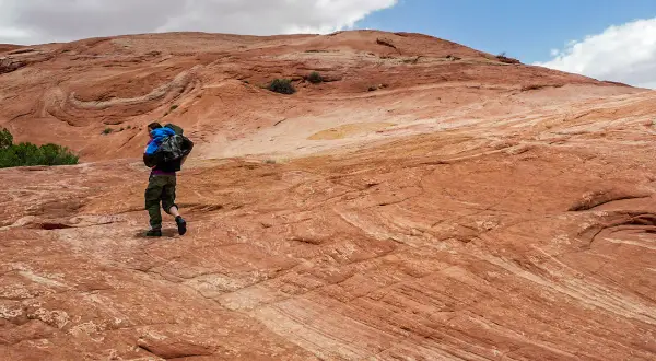 Wanderer auf rotem Felsplateau, wo die Moqui Marbles sich bewegen.