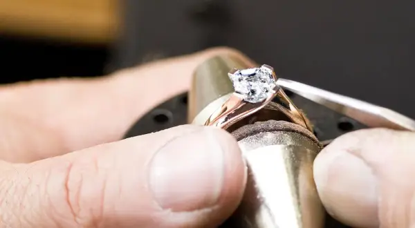 Ein Juwelier setzt einen funkelnden Diamanten, einen kostbaren Edelstein, in eine Ringschiene ein.