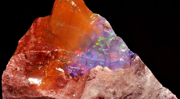 Ein roher Feueropal mit leuchtenden Farben, dessen feurige Wirkung durch das Spiel von Licht und Farbe im Stein fasziniert.