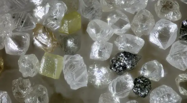 Unbearbeitete Diamanten, einige gelblich, andere klar, glänzen. Ihre Seltenheit und Härte erklären, warum sind Diamanten so wertvoll.