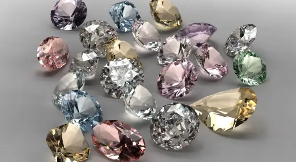 Bunte Edelsteine, was ist wertvoller als Diamant? Ein Haufen funkelnder, geschliffener Juwelen in Rosa, Blau, Grün und Gelb.