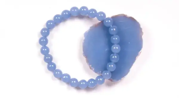 Armband aus hellblauen Perlen, die auf einem Stück Angelit Stein liegen.