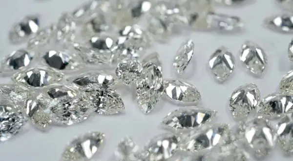 Glitzernde Diamanten in verschiedenen Schliffen, darunter Marquise und Tropfen, liegen verstreut. Ihr perfekter diamanten schliff fängt das Licht ein.