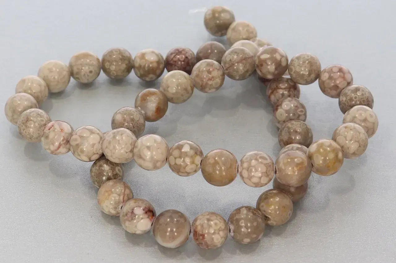 Zwei Stränge mit runden, beige-braunen Korallenperlen, die die Bedeutung von Schutz und Heilung symbolisieren.