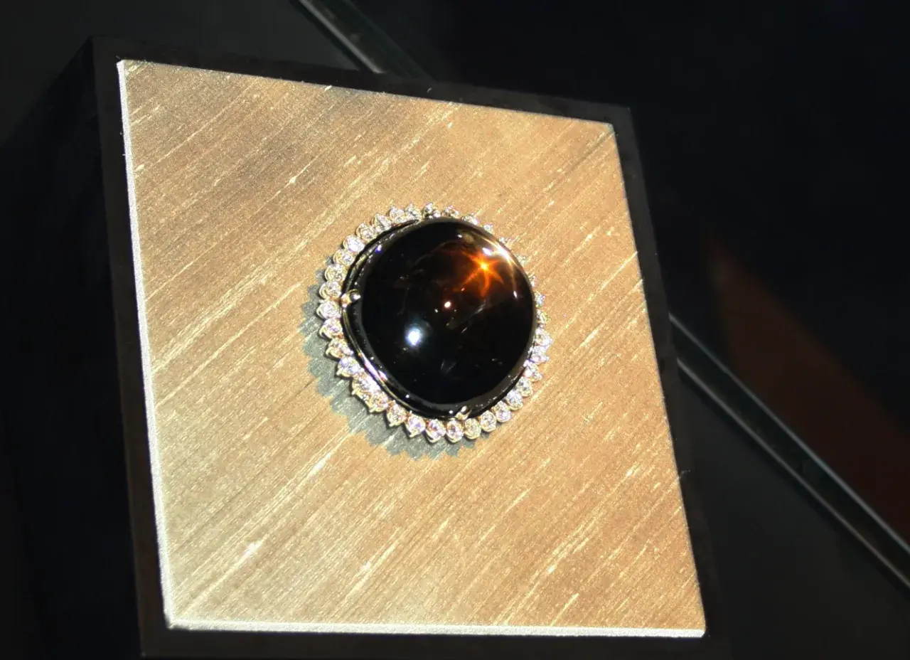 Ein glänzender schwarzer Saphir mit einem Stern-Effekt, umgeben von kleinen Diamanten. Seine geheimnisvolle schwarzer saphir bedeutung fasziniert.