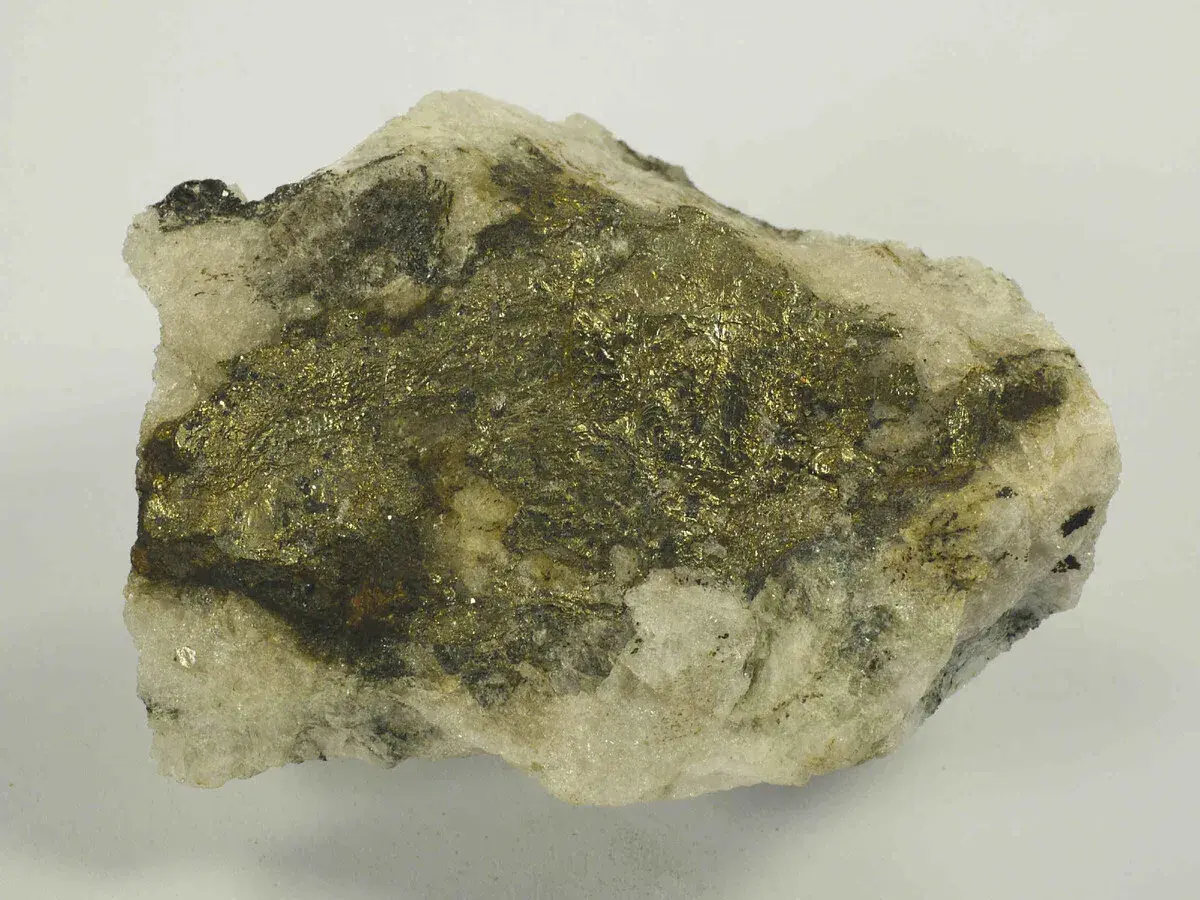 Gestein mit glänzenden, goldfarbenen Pyrit-Kristallen. Vorsicht, Pyrit ist giftig!