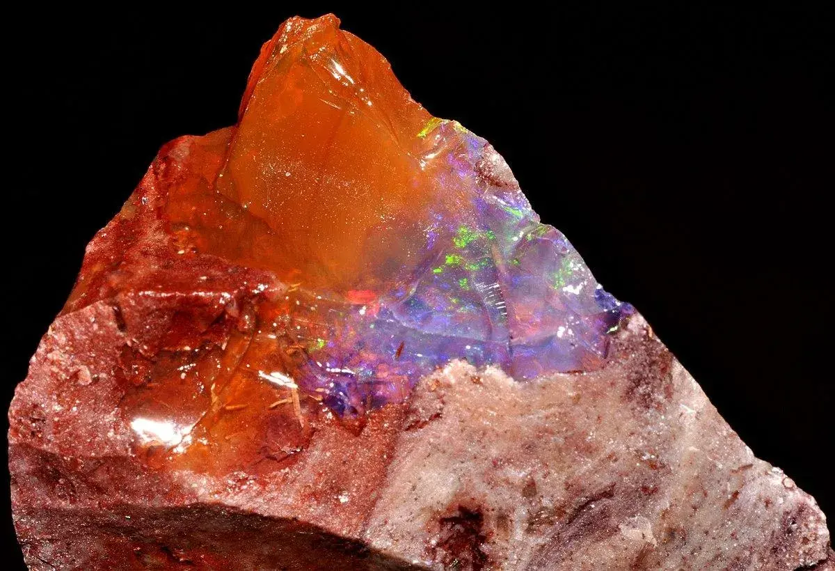 Ein roher Feueropal mit leuchtenden Farben, dessen feurige Wirkung durch das Spiel von Licht und Farbe im Stein fasziniert.