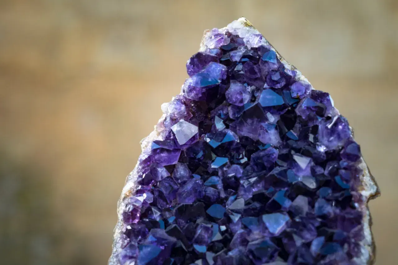 Ein glitzernder, tief violetter Amethyst-Kristall. Die lila Stein Bedeutung wird oft mit Ruhe und Klarheit assoziiert.