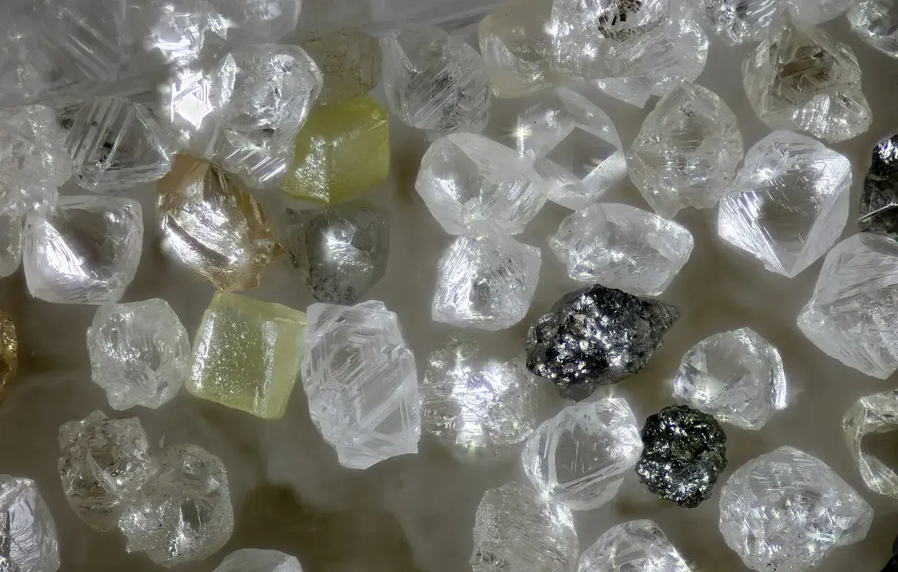 Unbearbeitete Diamanten, einige gelblich, andere klar, glänzen. Ihre Seltenheit und Härte erklären, warum sind Diamanten so wertvoll.