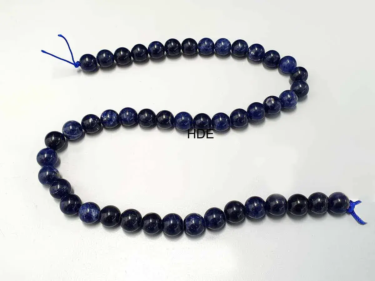 Eine Kette aus tiefblauen Sodalith-Perlen, die auf einem weißen Hintergrund liegen.